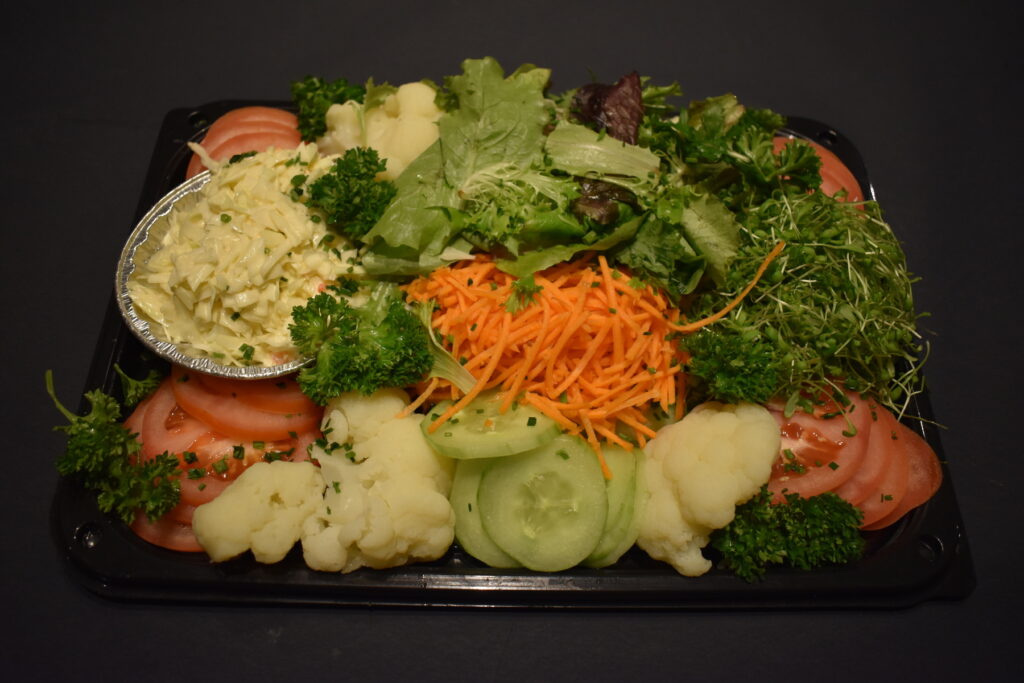 Schotel met verse groentjes zoals bloemkool, broccoli, wortel, komkommer en sla als bijgerecht bij de gourmet