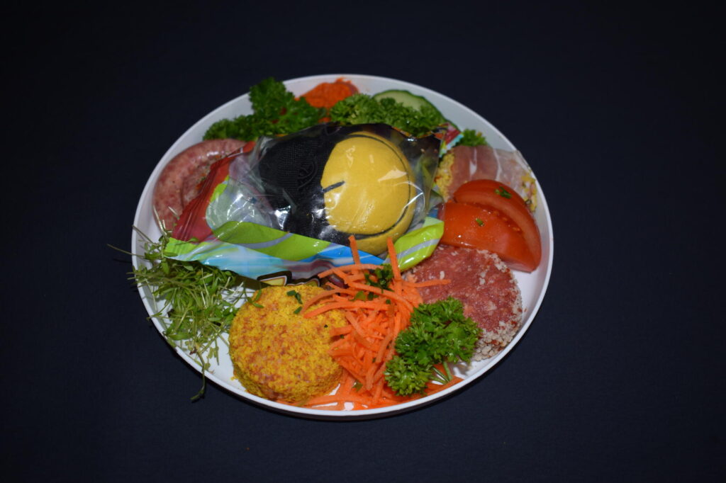 Junior gourmetschotel voor kinderen met een hamburgertje, gepaneerd vlees, groentjes en een verrassing in zilverpapier