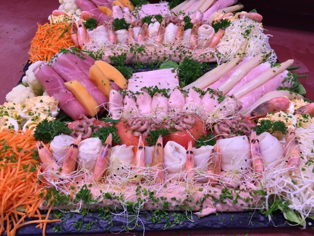 Koude vlees- en visschotel met hamrolletjes, garnalen, gamba's, asperges en meloen