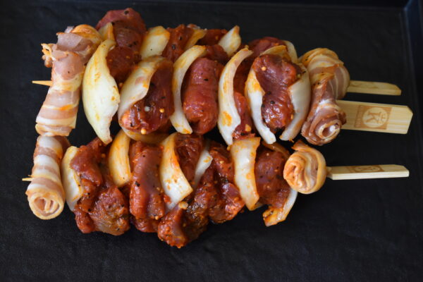 Rauwe gemarineerde brochettes met stukjes vlees en ui, klaar om op de barbecue te leggen